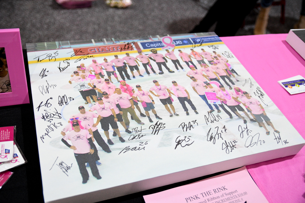 Players, Coaches, And Staff Stand In The Shape Of A Breast Cancer Ribbon For One Of The Canvases
