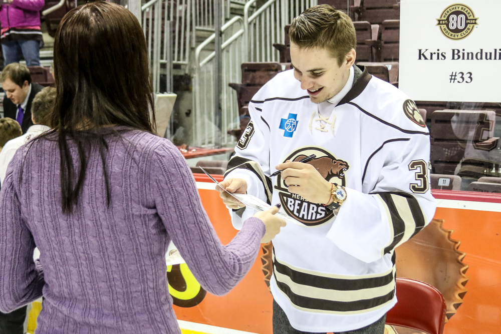 Kris Bindulis Smiles As He Is Handed An Item To Sign